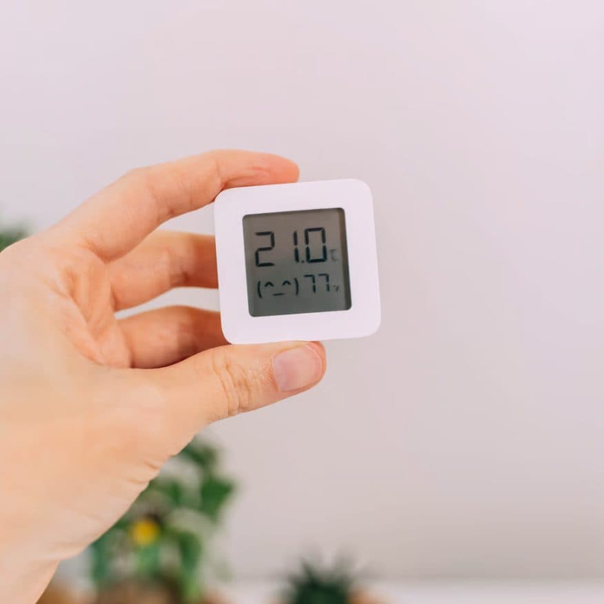 A hygrometer held in the hand, reading 77 % humidity.